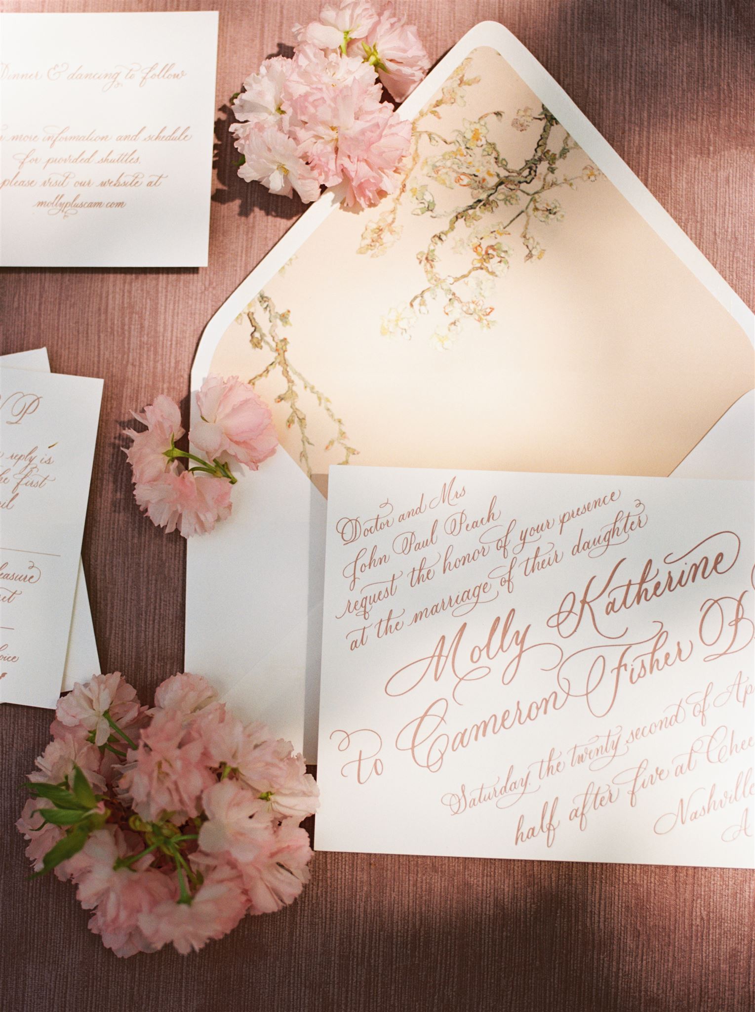 Flat lay of invitation suite boasting florals and full spot calligraphy.