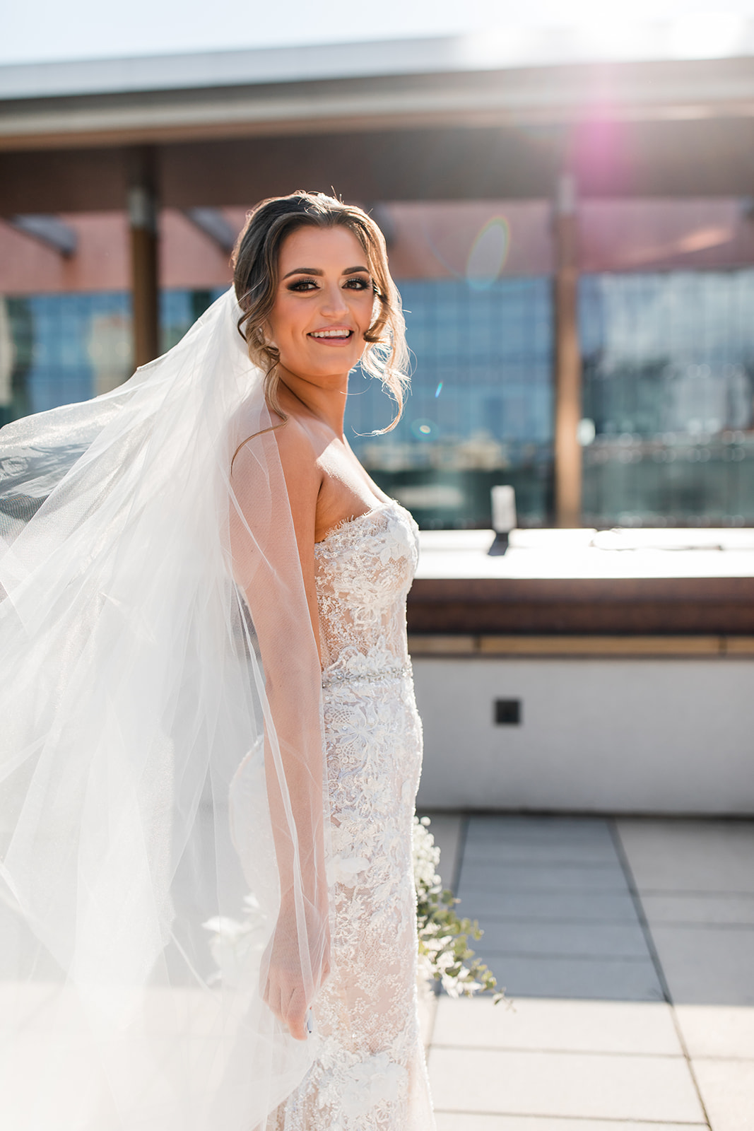 Bride smiling with veil blowing in the wind.