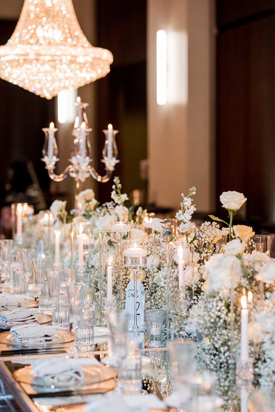 Formal tablescape of dinner setting, florals, lighting, table numbers and menus.