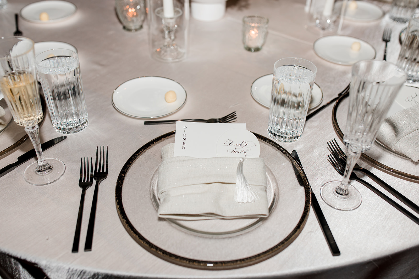 Formal table setting with custom menu tucked into napkin on plate.