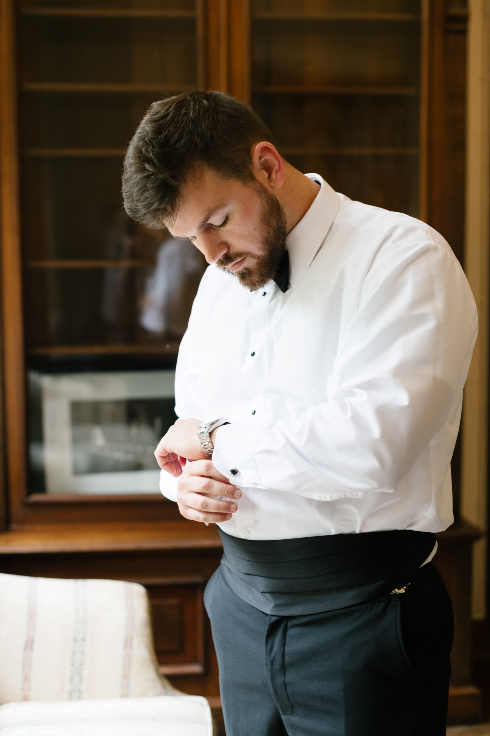 groom in suit looking down to fix cufflinks.