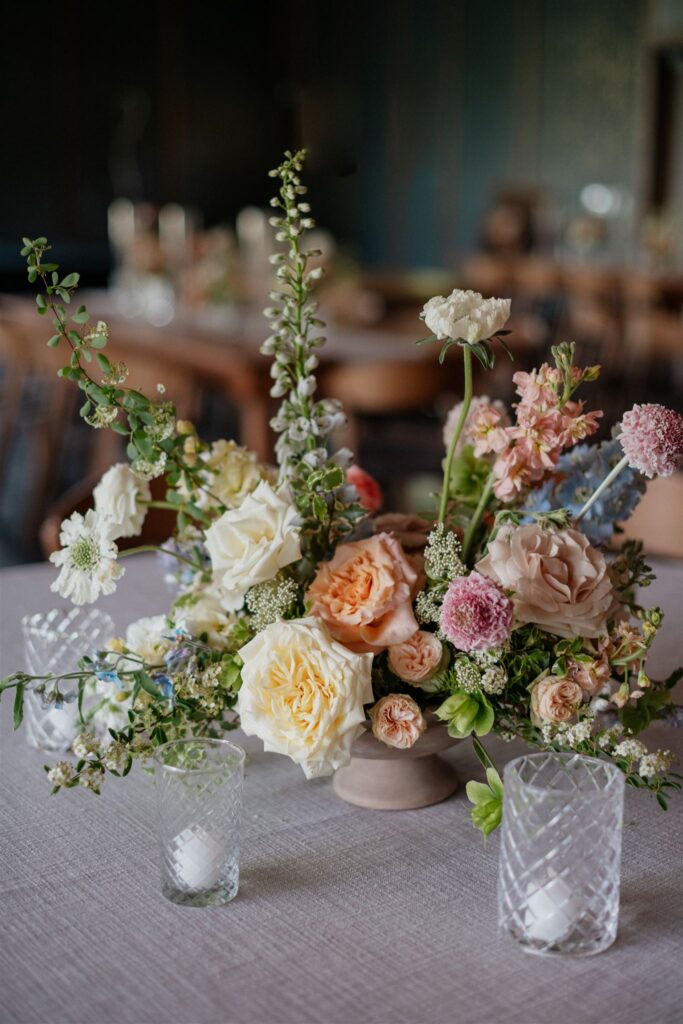 Floral arrangement decor sits on top of white-linen dining table.