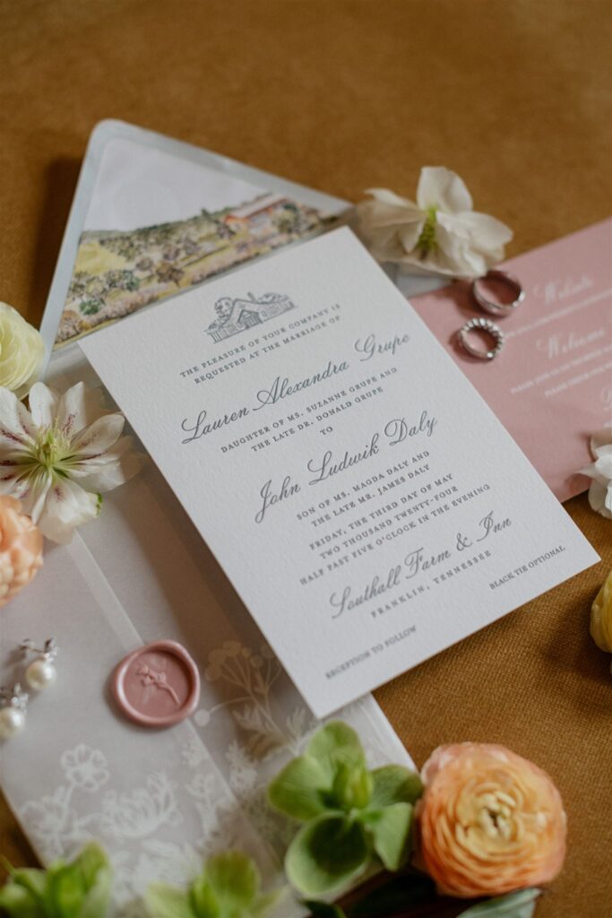 Flat lay of formal wedding invitation suite decorated with flowers.