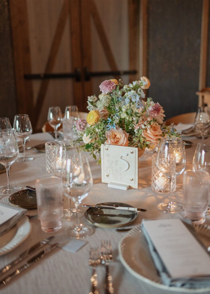 Formal reception dining place setting with table menus, candles and floral arrangements.