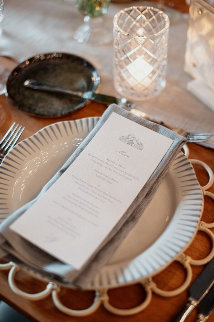 Printed menu sitting atop formal place setting at reception table.