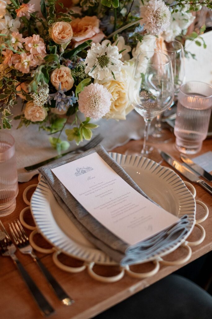 Printed menu sitting atop formal place setting at reception table.