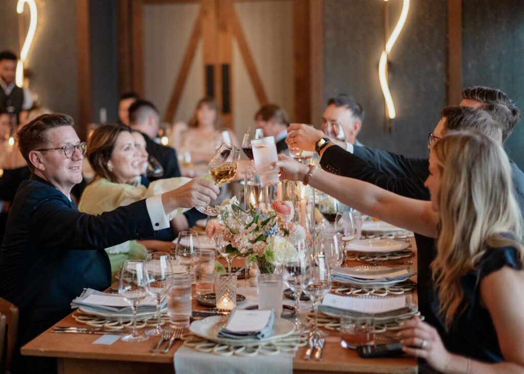 Guests seated at reception table making a toast.