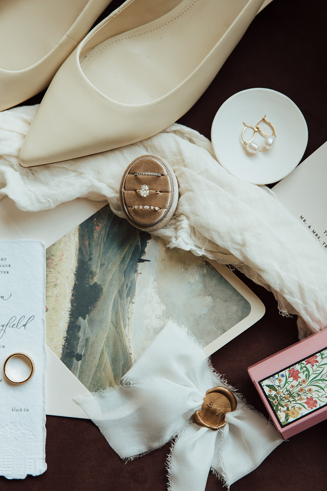 Styled flat-lay to include invitation suite, showcasing custom envelope liner of hills and countryside scene.