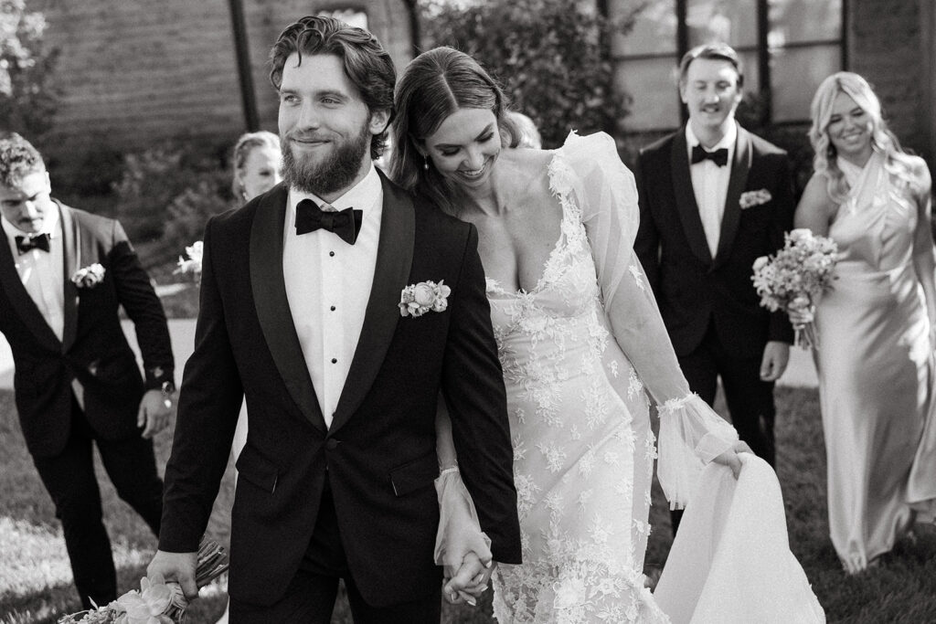 Bride and Groom walk hand in hand down the aisle as they smile.