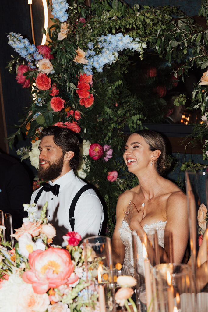 Bride and Groom seated at head table as they look ahead with smiles.