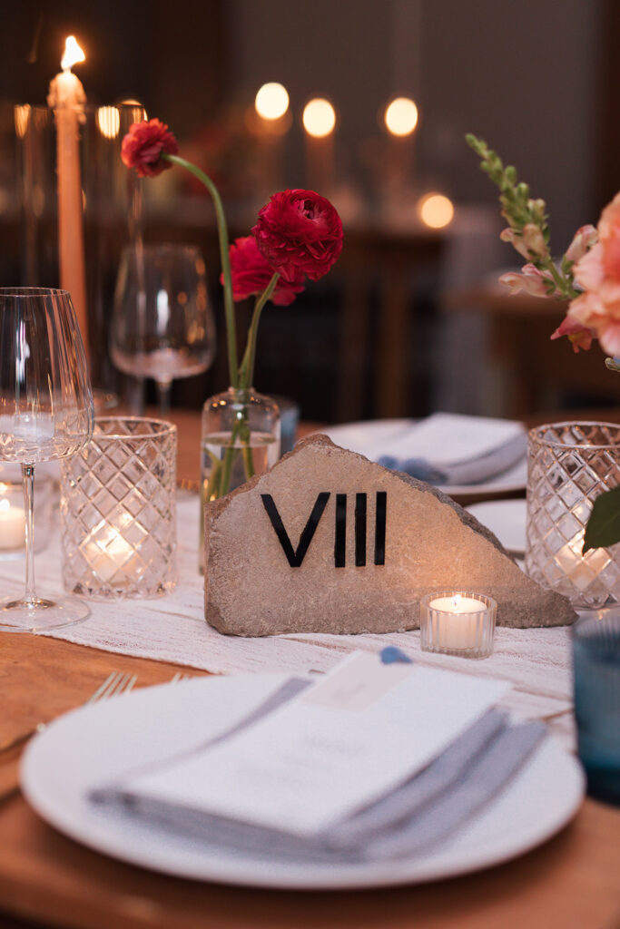 Formal reception table setting with stone, Roman numeral table number in center.