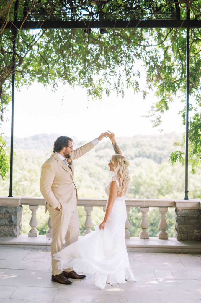 Bride and Groom sharing a twirl beneath a canopy of wisteria  with mountains in the background. 