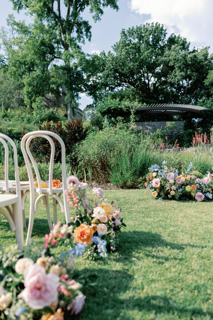 floral arrangements line the aisle of an outdoor wedding venue.