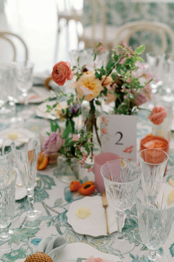 Formal wedding reception tablescape complete with florals, glassware, plates, cutlery, candles, and custom table numbers.