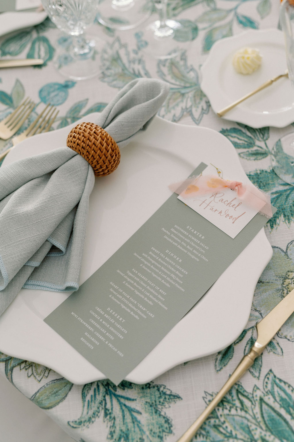 A custom reception menu sits atop formal place setting beside linen napkin.