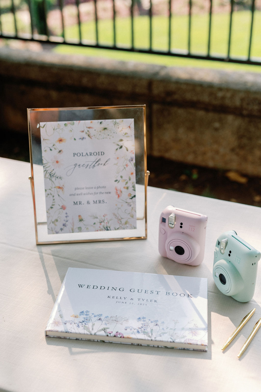 Guest book table signage with guestbook and polaroid cameras.