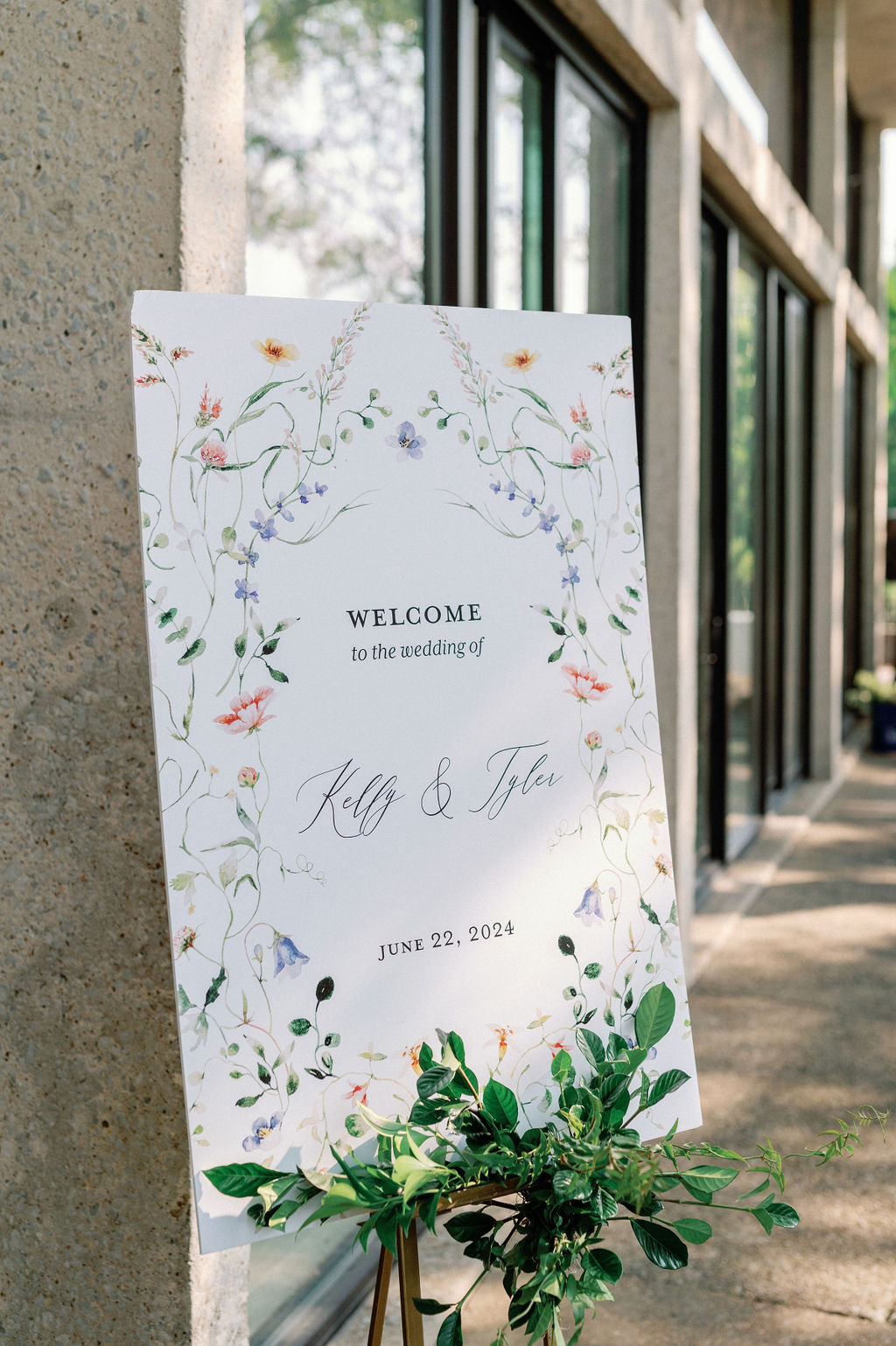 Custom garden-inspired wedding welcome sign styled with florals along the floor.