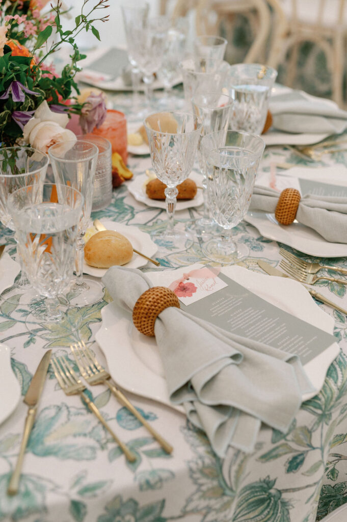 Formal wedding reception tablescape complete with florals, glassware, plates, cutlery, candles, and custom table numbers and menus.