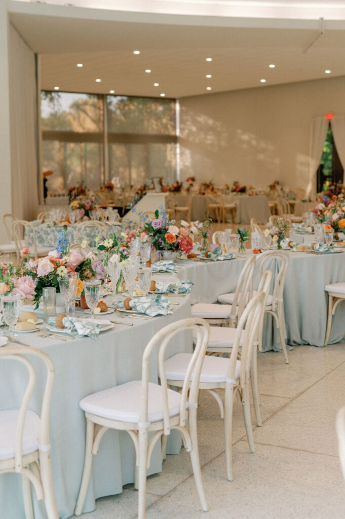 Formal wedding reception tablescape complete with florals, glassware, plates, cutlery, candles, and custom table numbers and menus.