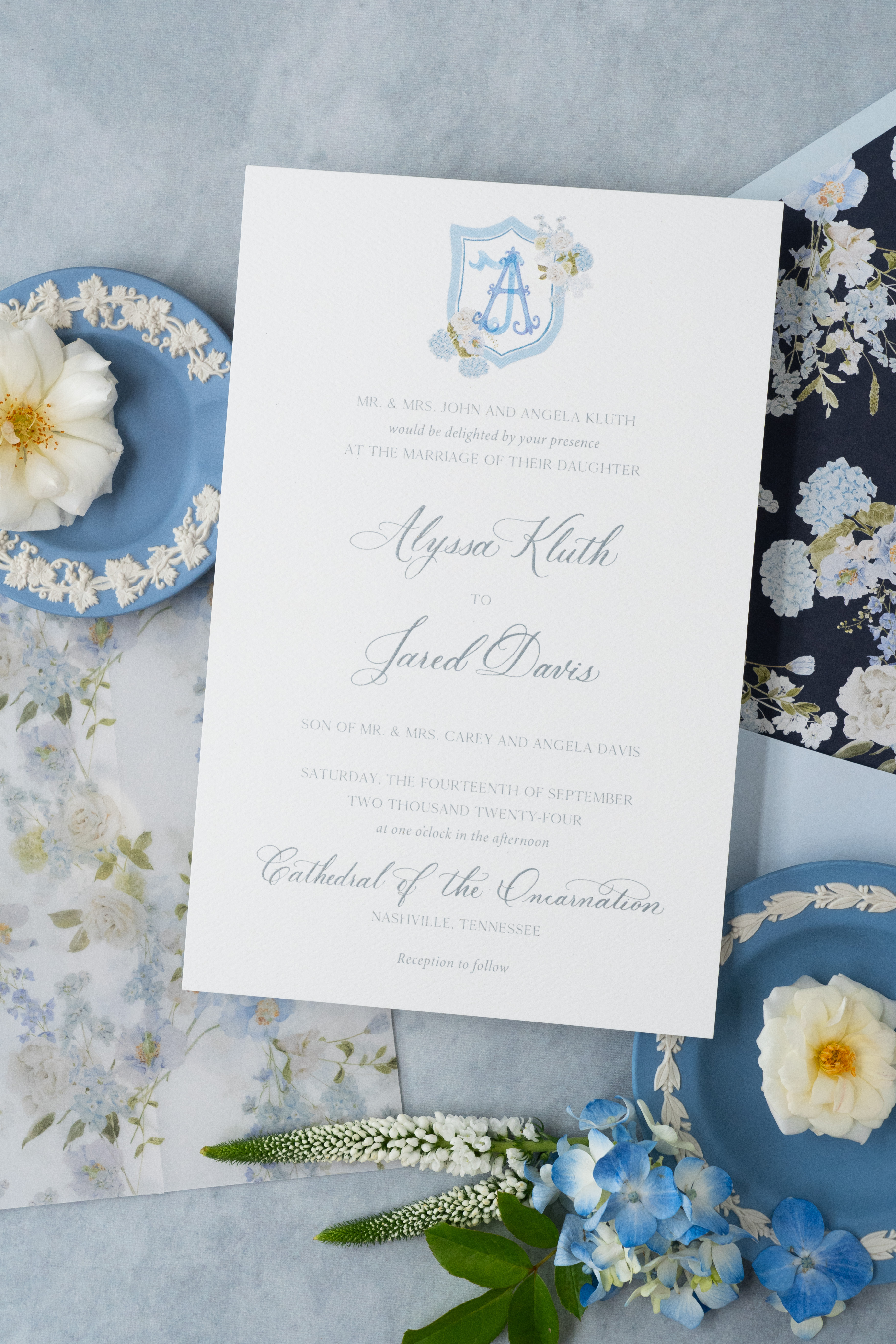 Custom wedding invitation suite flat lay styled with florals and vintage decor.