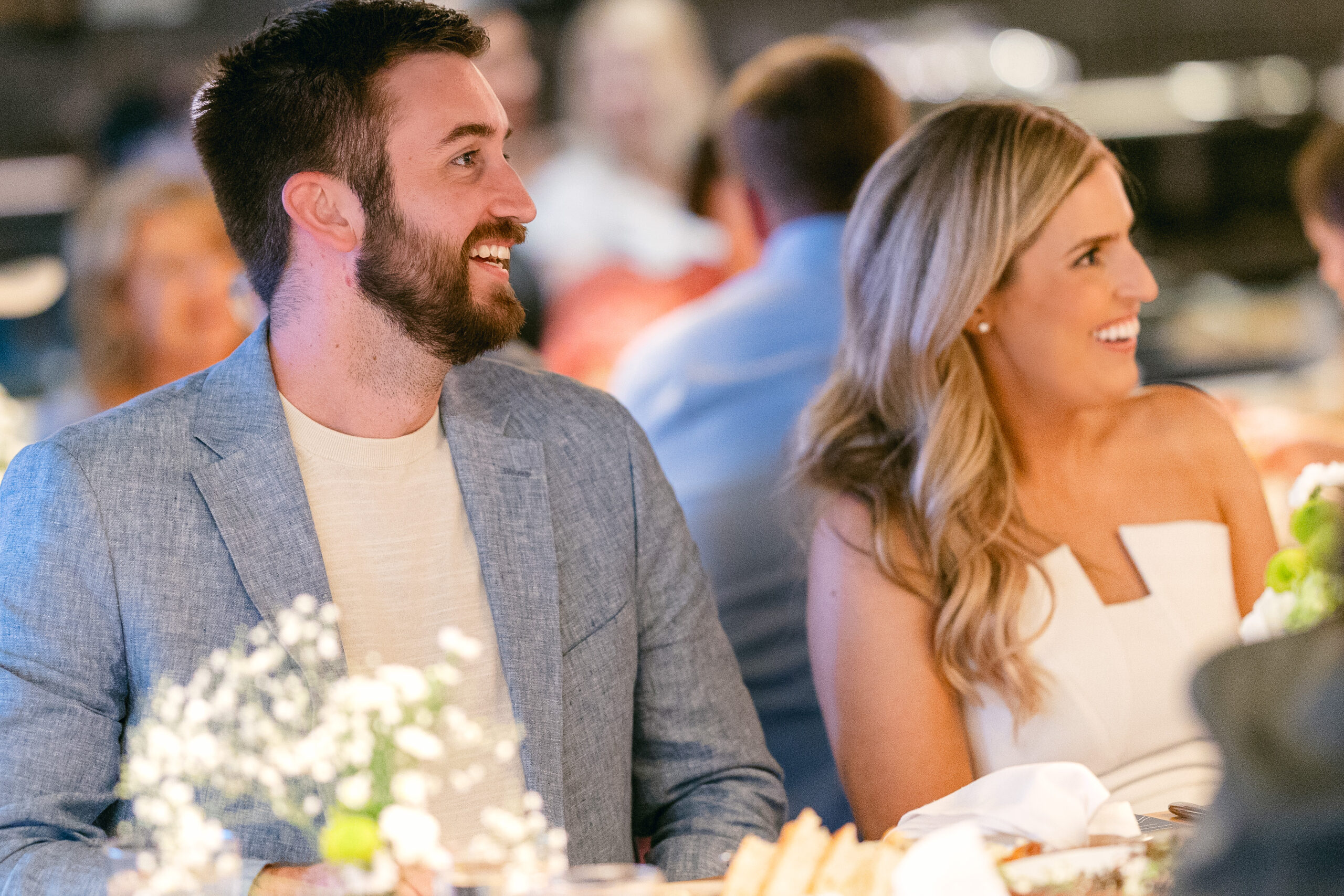 Bride and groom-to-be sharing a smile while seated at their rehearsal dinner table.