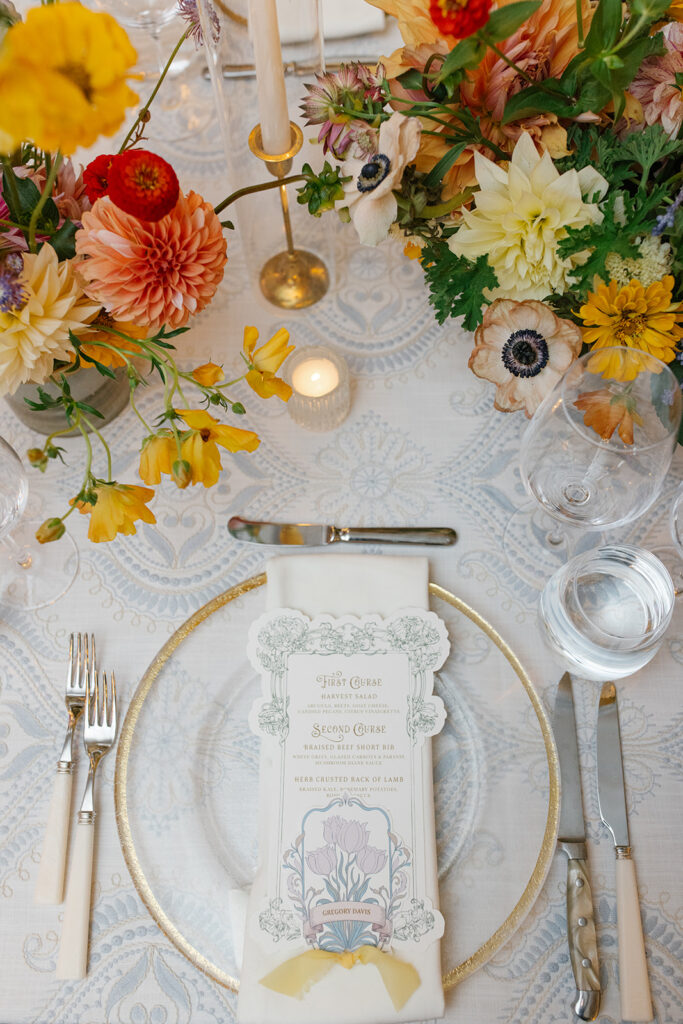 Custom die-cut menu placed atop recption table plate setting. includes place card, and yellow chiffon ribbon.