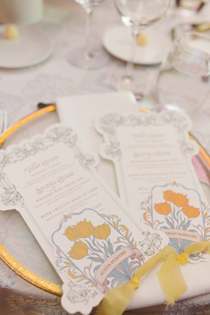 Custom die-cut menu placed atop recption table plate setting. includes place card, and yellow chiffon ribbon.