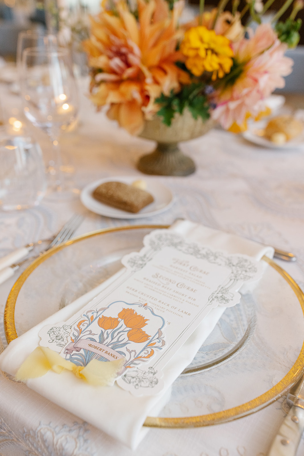 Custom die-cut menu placed atop recption table plate setting. includes place card, and yellow chiffon ribbon.