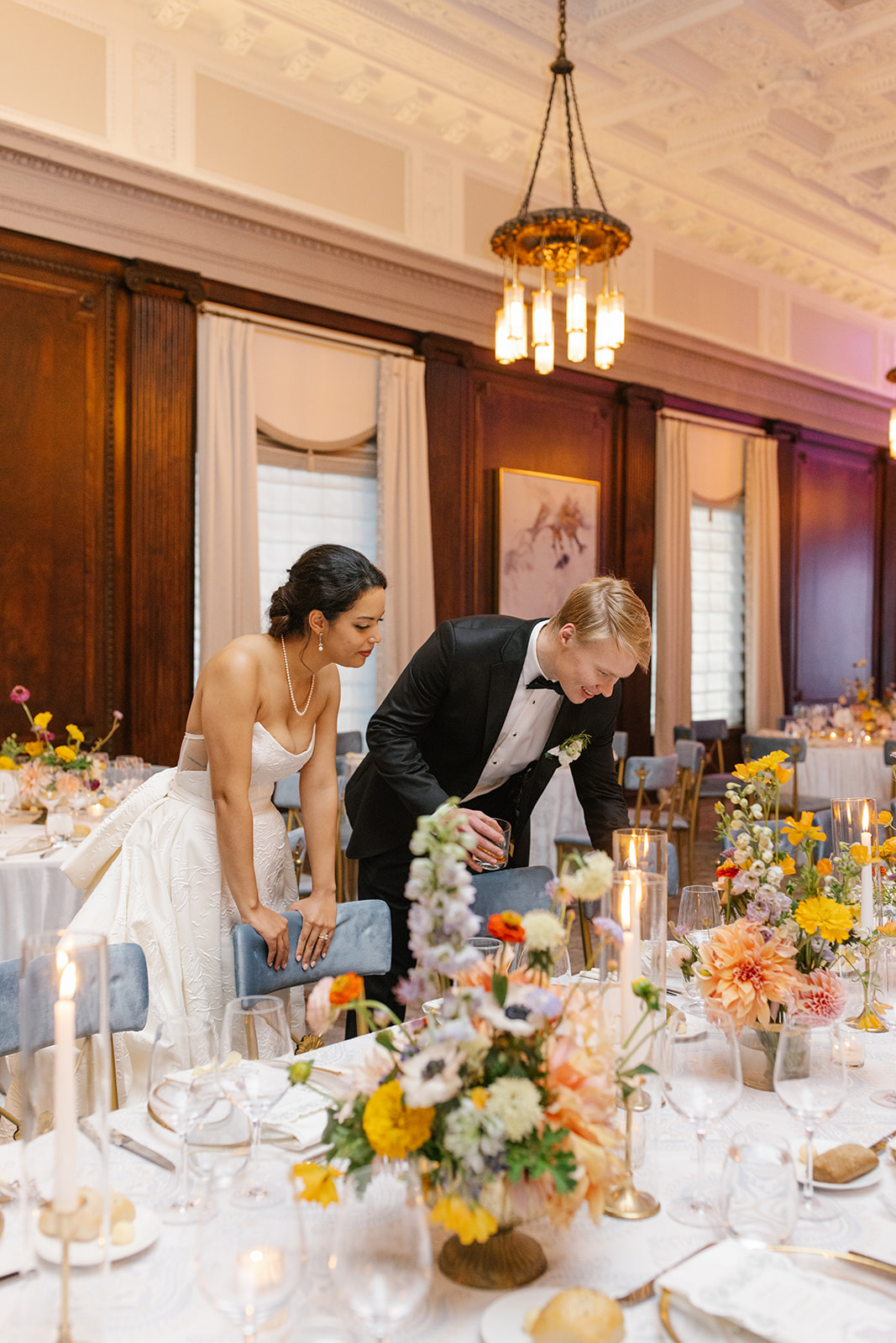 Bride and groom observe reception table details together.