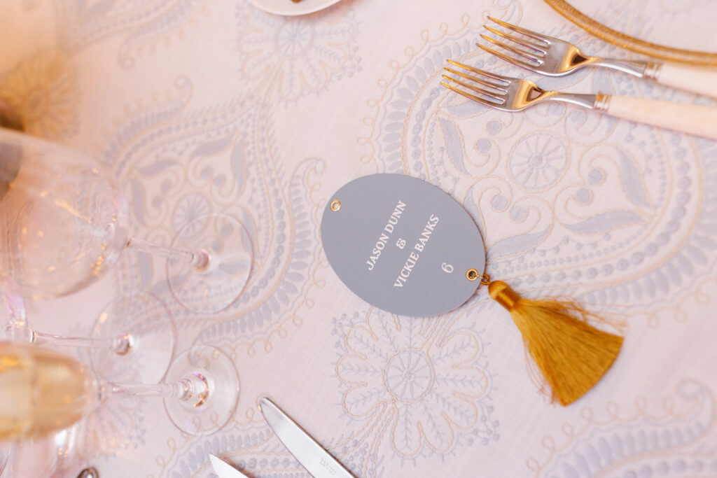 Escort tag with tassel lays on reception table by tableware.