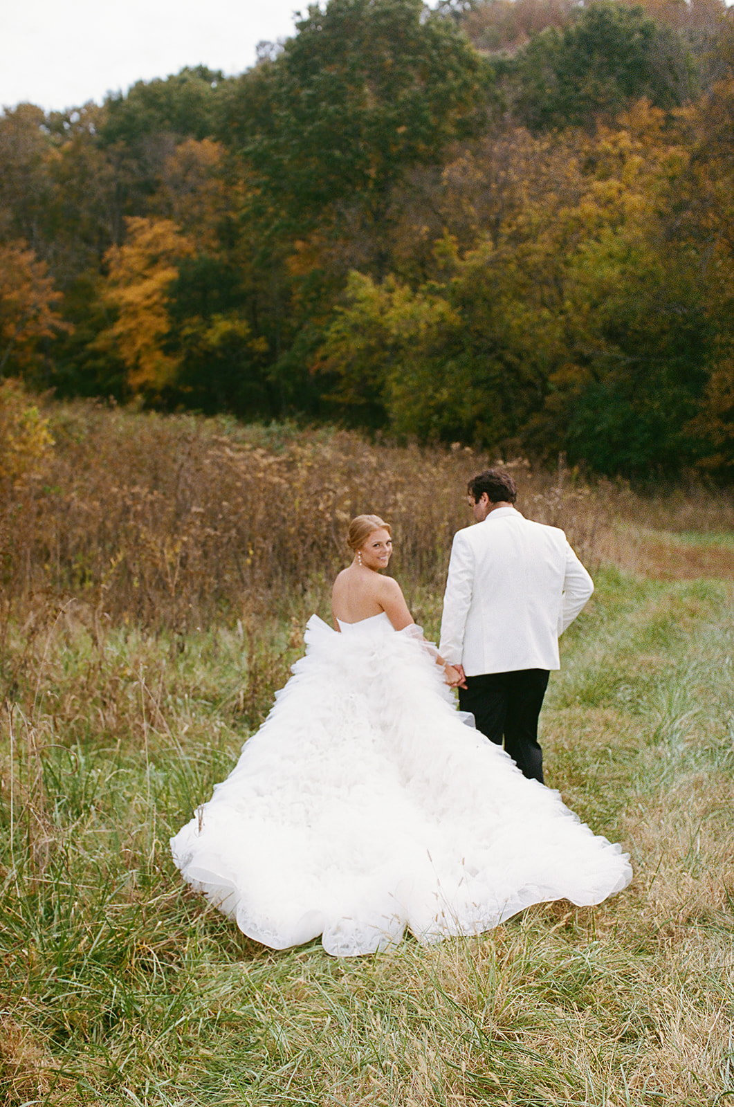 bride and groom hold hands as they walk down grassy path in Nashville