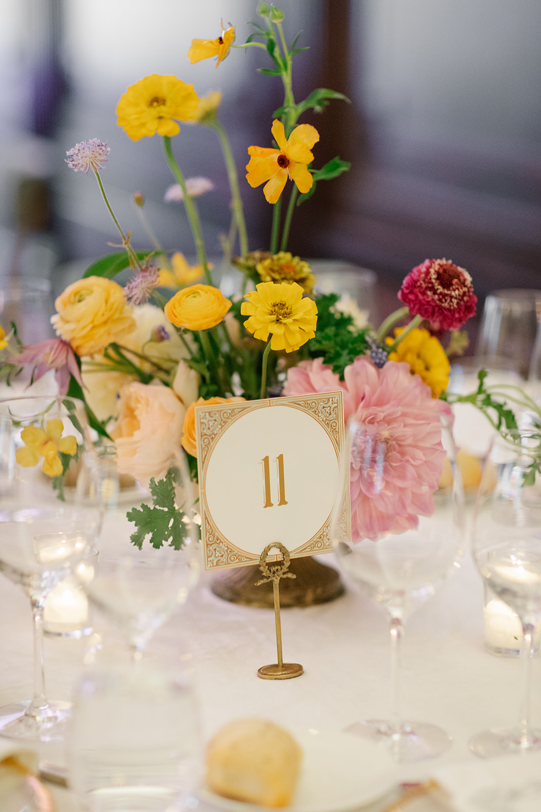 Formal reception table setting includes floral arrangements, glassware, and custom table number signage.