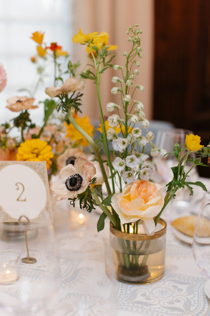 Formal reception table setting includes floral arrangements, glassware, and custom table number signage.