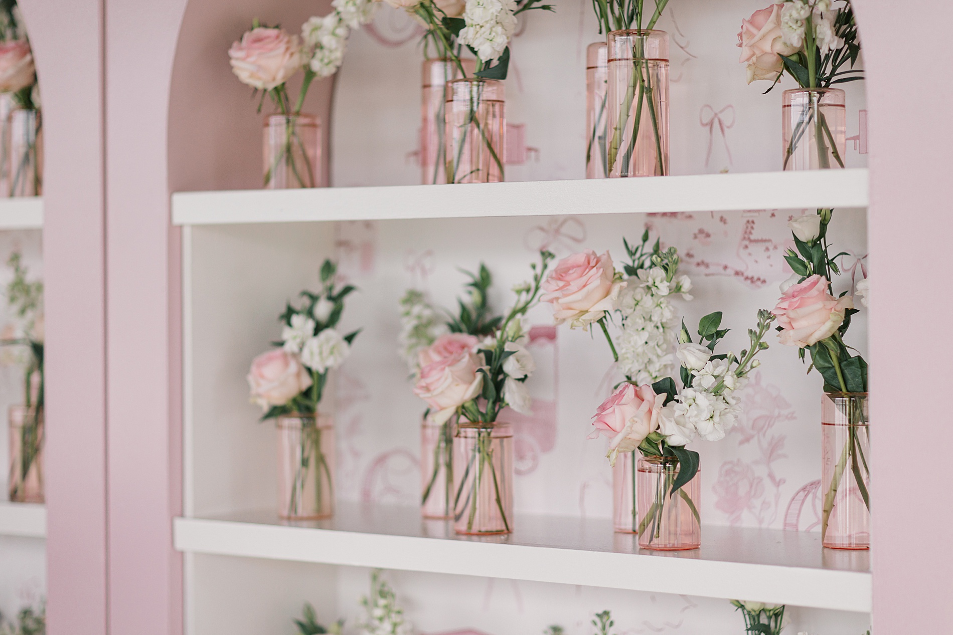 shelves hold pink cups with pink flowers and white flowers