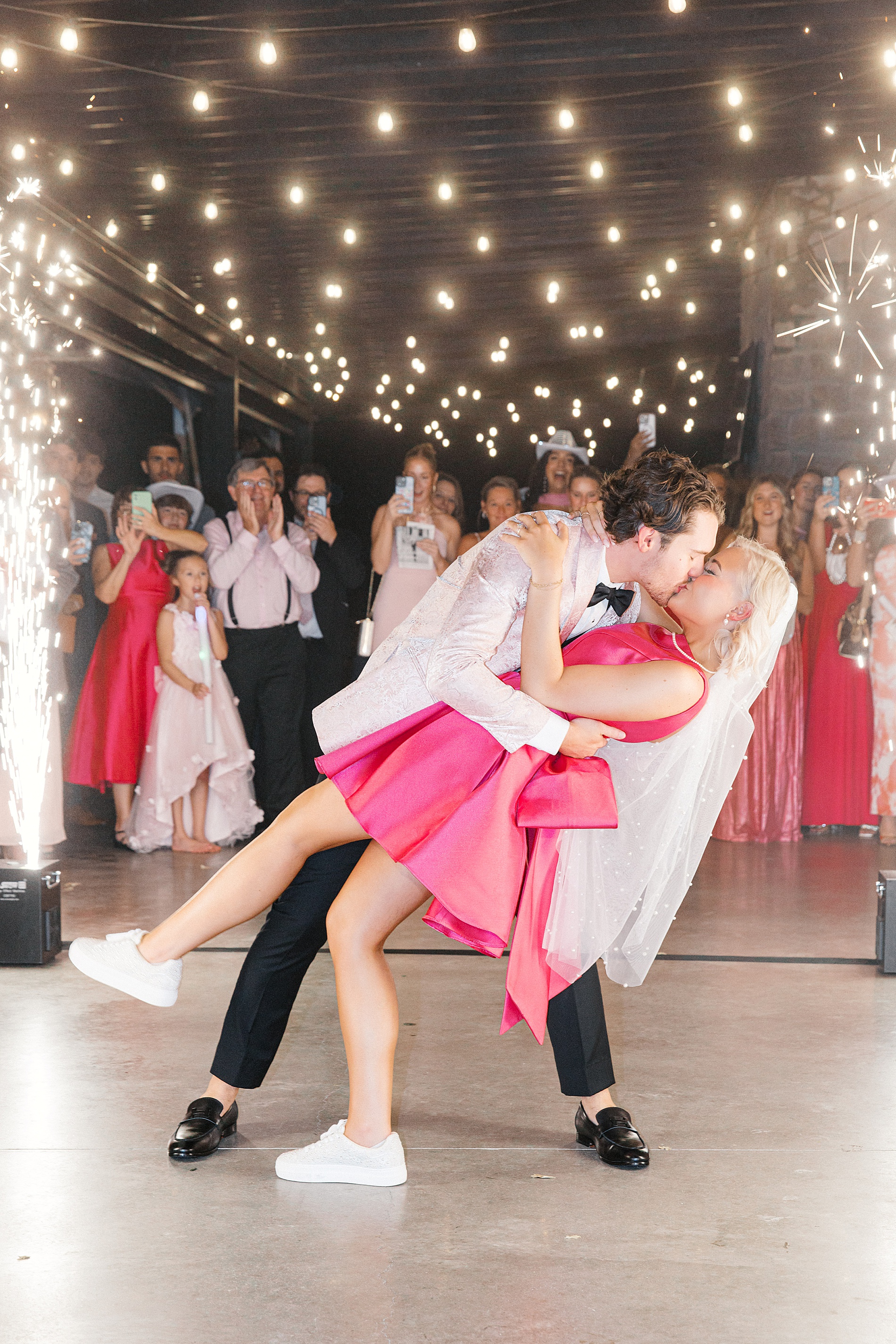 bride in hot pink dress kisses groom as they exit wedding