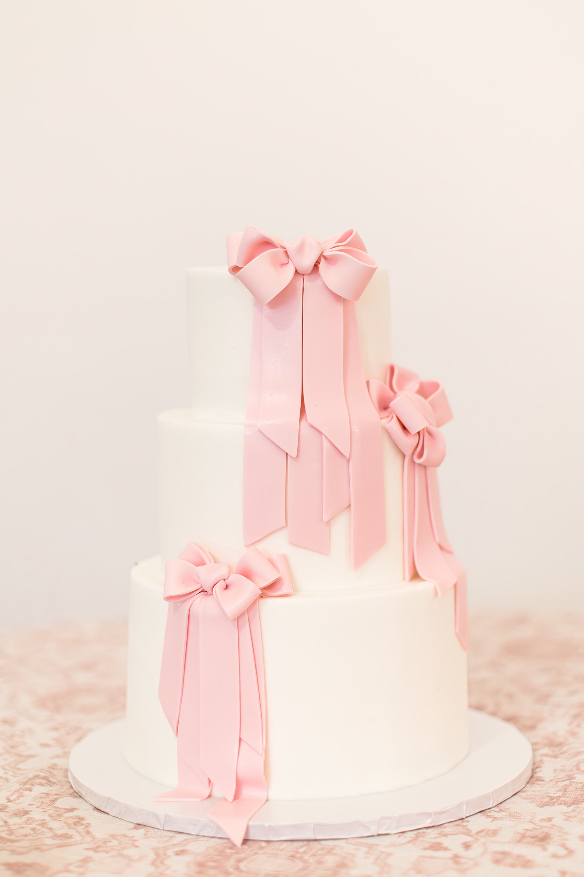 white wedding cake with pink bows