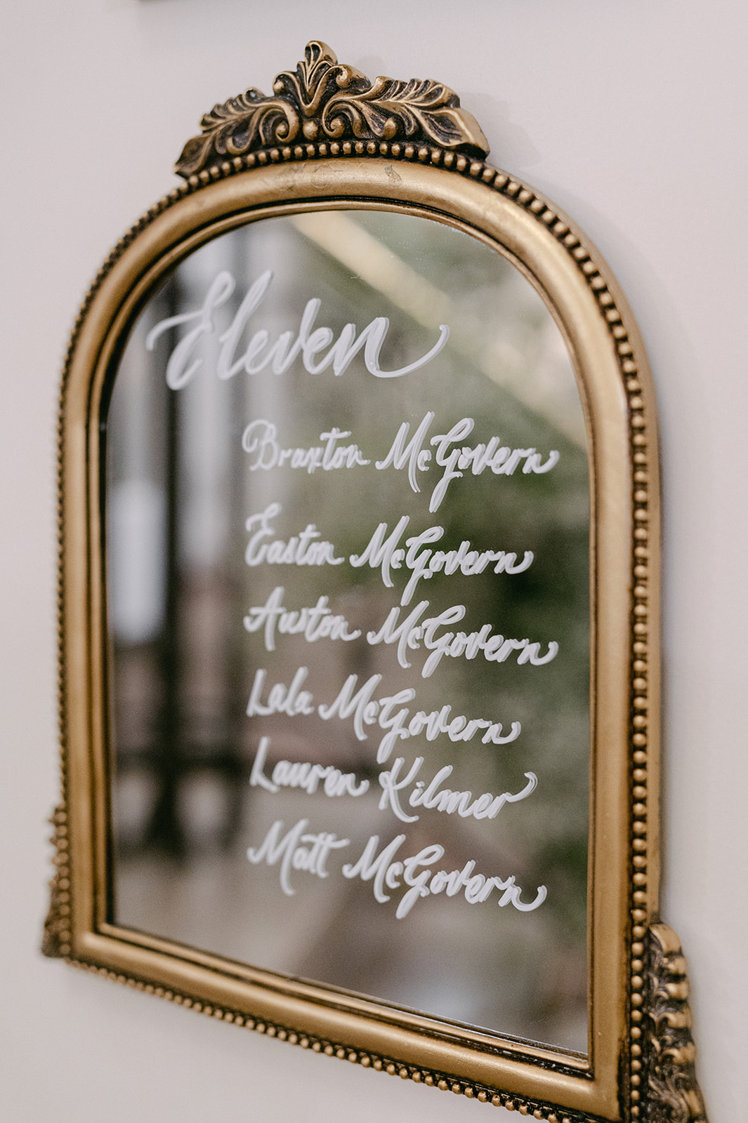 vintage gold framed mirror seating chart with guests names in white calligraphy 